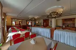 Tilava ruokasali kattaneilla pöydillä